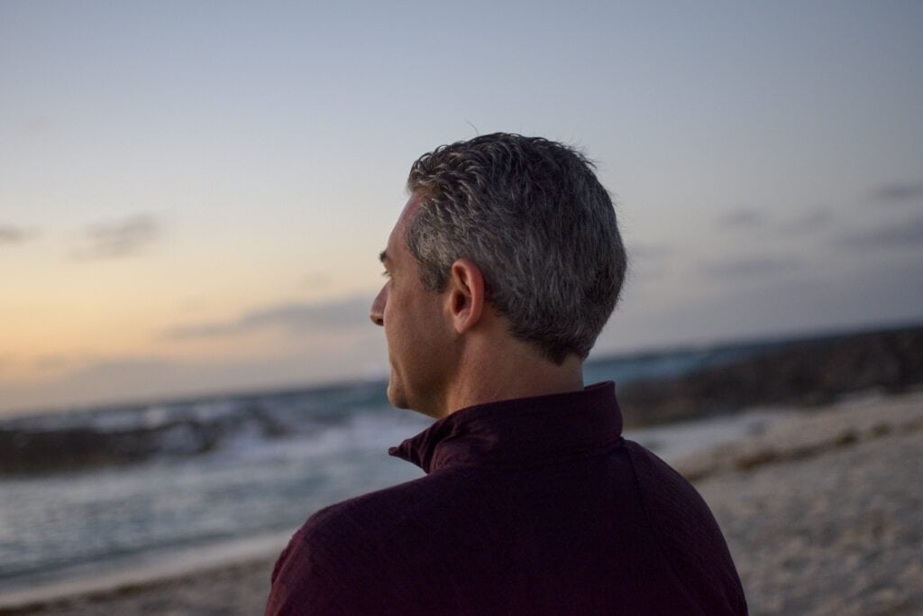 Man looking out at the ocean at dusk.
